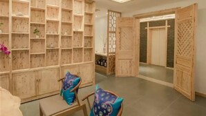 A room with wooden shelving units, a seating area with chairs, and a door leading to another room. - Floral Hotel Qingshe Chengdu (Chengdu)