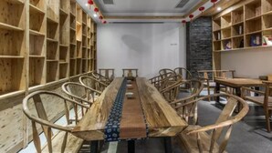 A room with a long wooden table and chairs, wooden shelves on the walls, and red lanterns. - Floral Hotel Qingshe Chengdu (Chengdu)