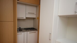 A compact kitchen with white cabinets, a gas stove, and a sink. - Casamare (Lignano Sabbiadoro)