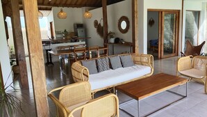 A spacious living area with a sofa, chairs, a coffee table, and a kitchen in the background. - Villa Manik (Canggu)