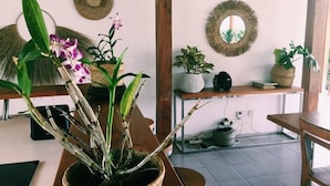 A room with a wooden table, potted plants, a woven basket, and a mirror on the wall. - Villa Manik (Canggu)