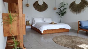 A bedroom with a wooden bed, a round woven rug, and a hanging plant. - Villa Manik (Canggu)