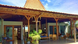 A covered outdoor area with a tiled roof, wooden beams, and hanging plants. - Villa Manik (Canggu)