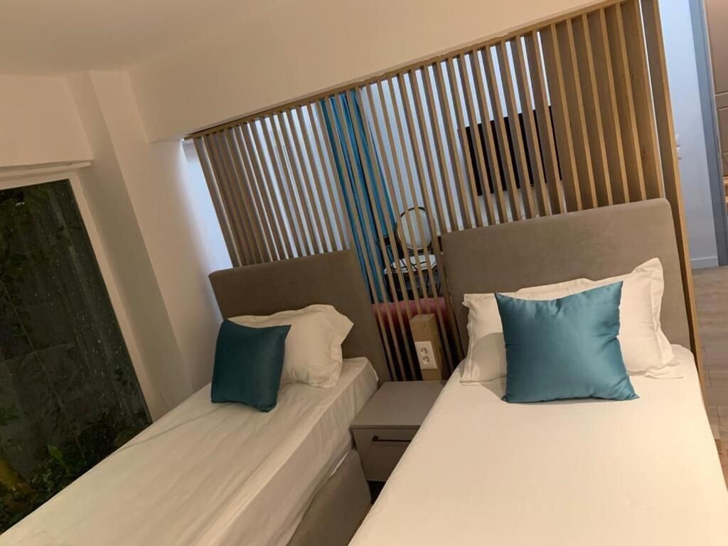 A hotel room with two beds, each with a pillow and a nightstand.