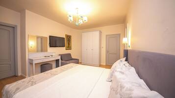 Un dormitorio con cama, escritorio, silla, armario y televisor en la pared.