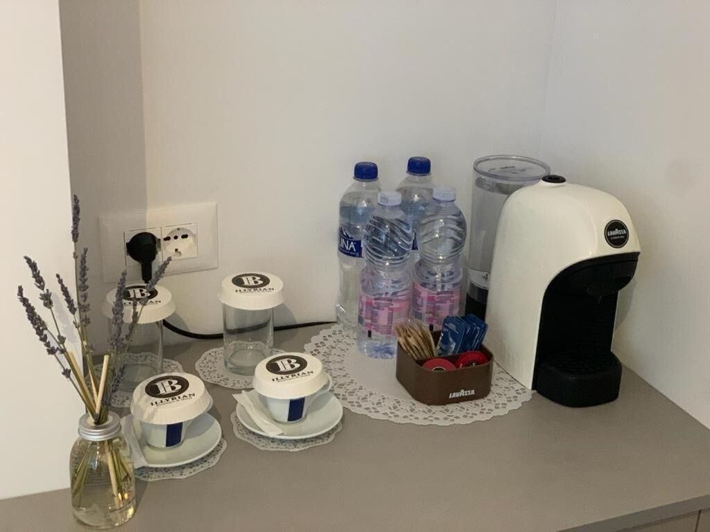 A table with water bottles, a coffee machine, and jars labeled 'Lavazza' on a hotel counter.
