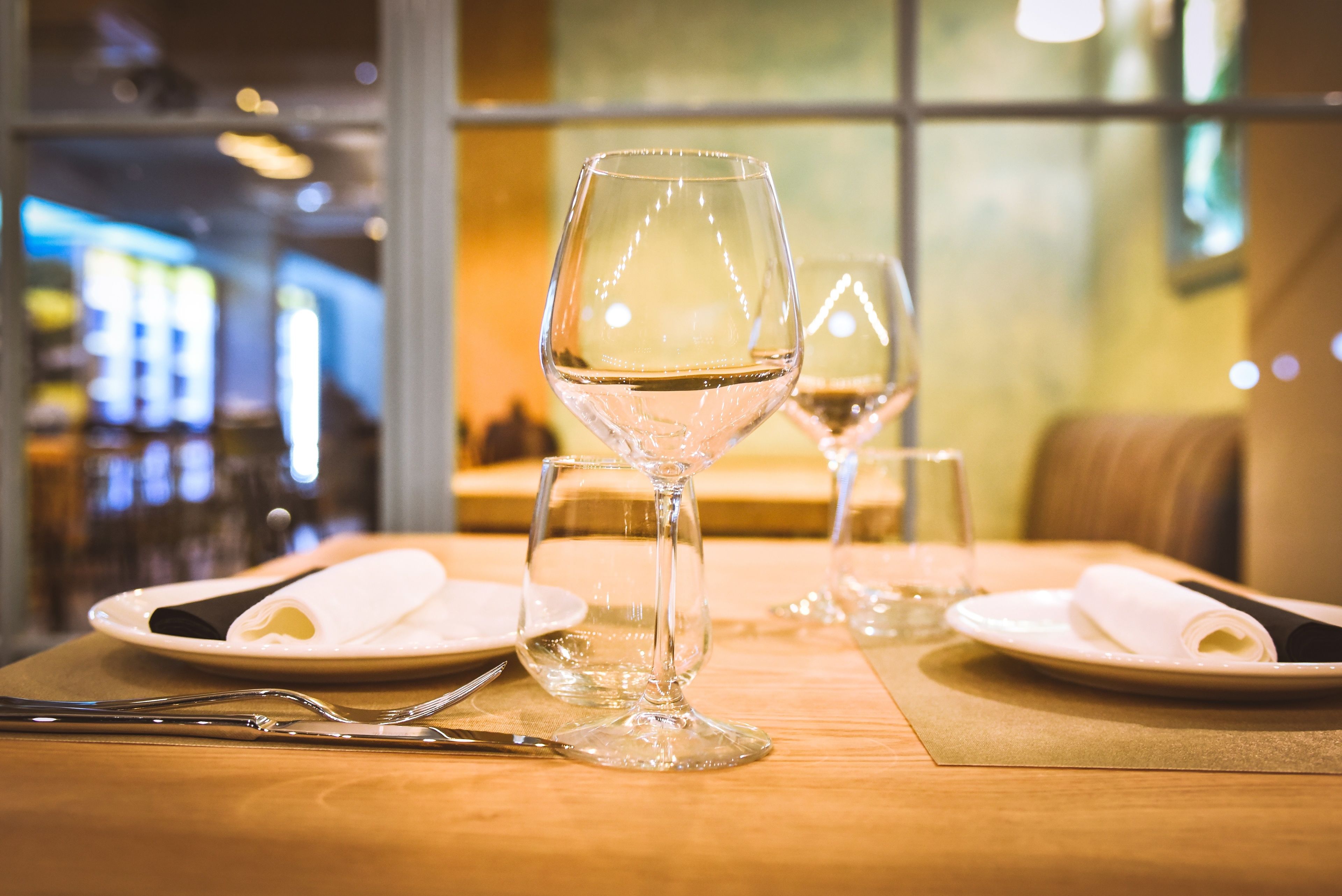 Une table à manger avec deux verres à vin, des assiettes et des couverts.