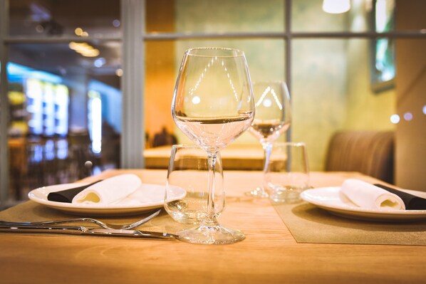 Una mesa de comedor con dos copas de vino, platos y cubiertos.