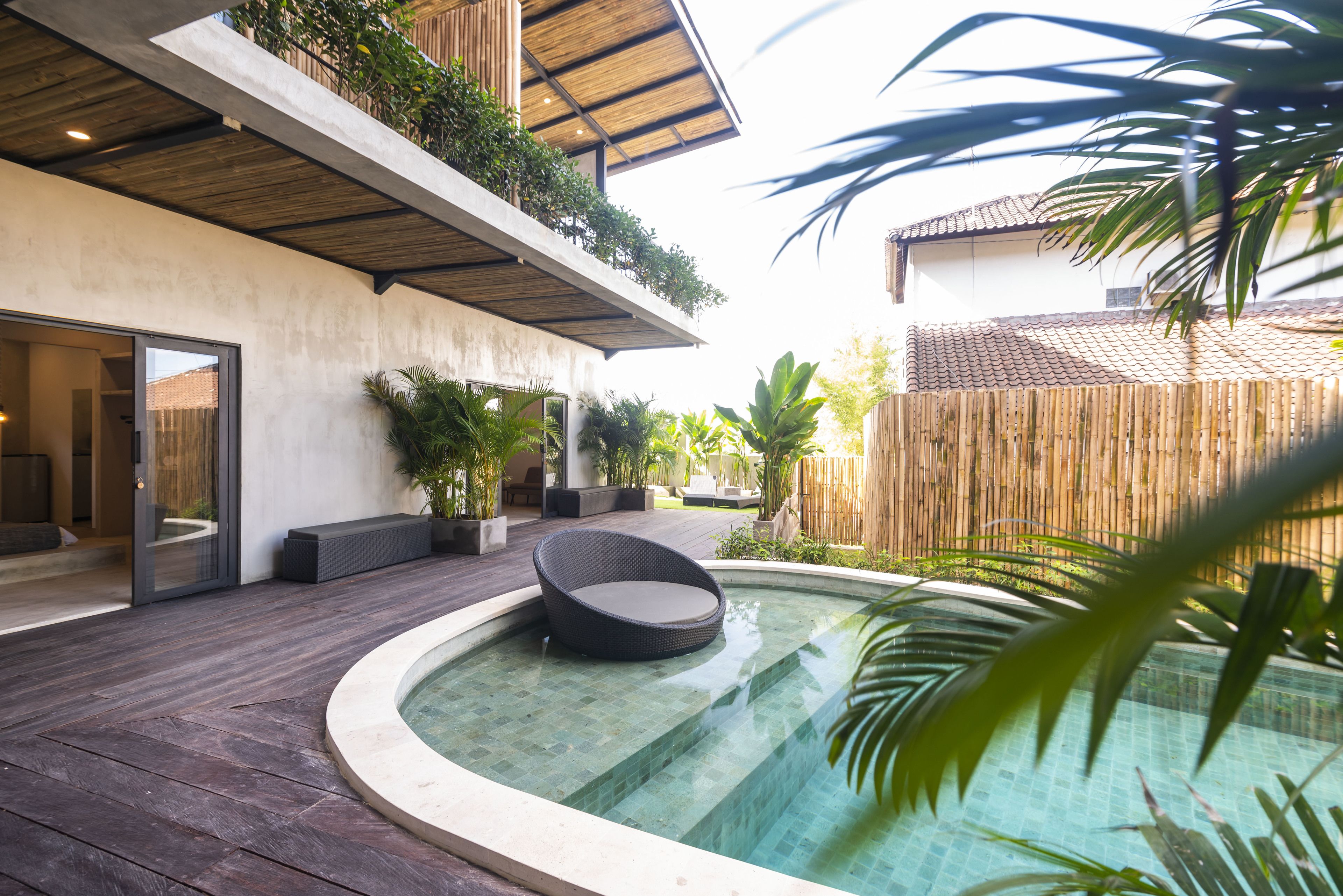 A modern outdoor pool area with a circular design, wooden deck, and a seating area with a chair.