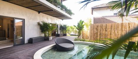 A modern outdoor pool area with a circular design, wooden deck, and a seating area with a chair.