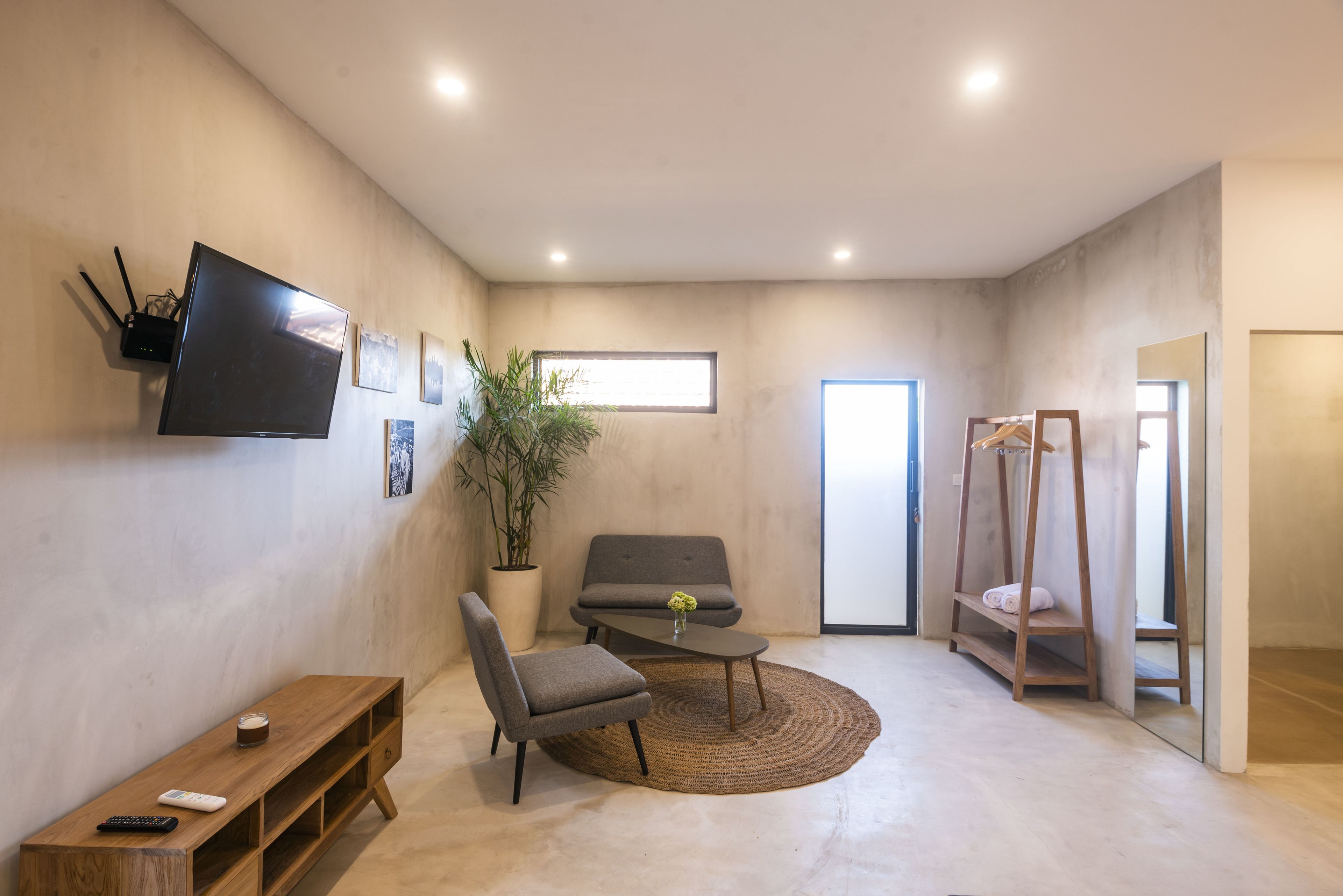 A modern living room with a flat-screen TV, a sofa, a coffee table, and a potted plant.