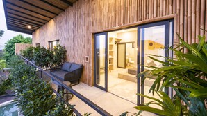 Ein modernes Haus mit Holzfassade, einem Sitzplatz auf dem Balkon und einer Glastür, die zu einem Innenbereich führt.