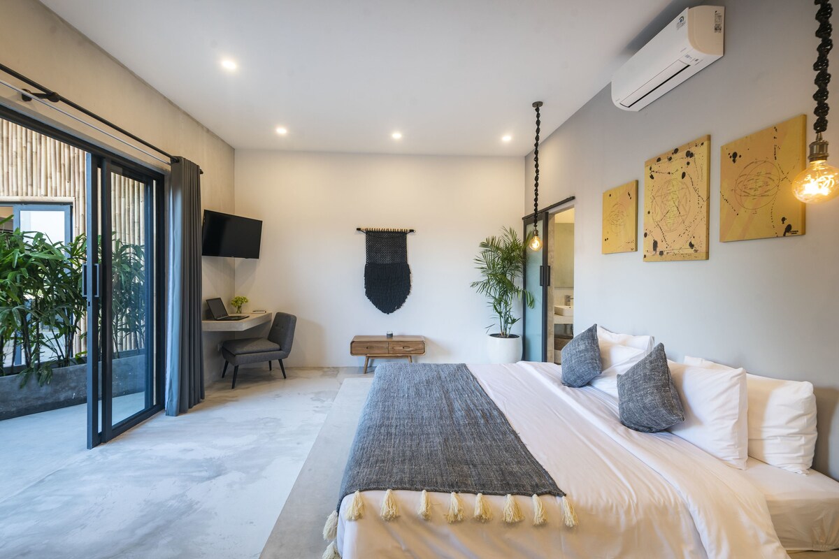 A modern bedroom with a large bed, a desk, and a TV.