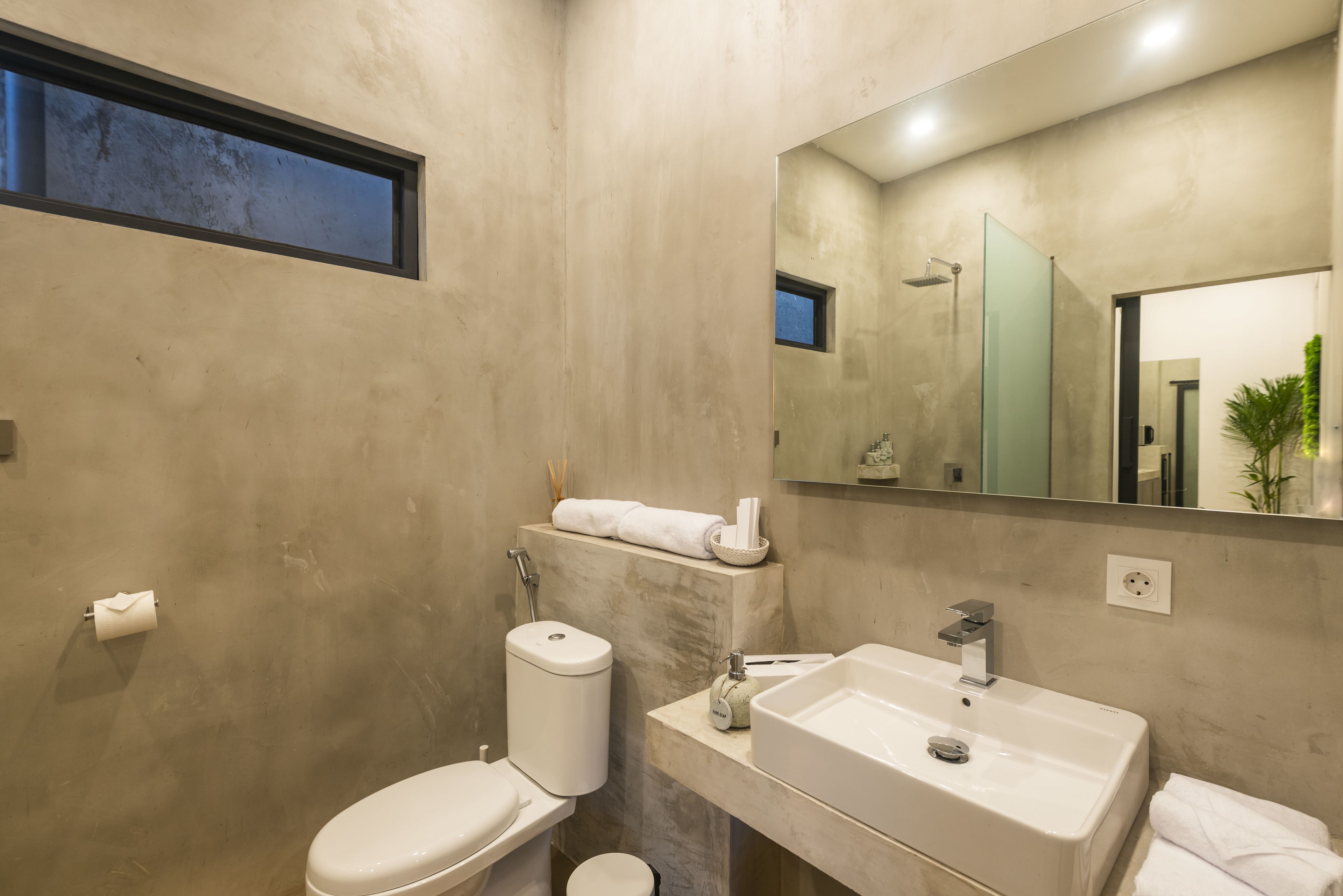 Une salle de bain moderne avec des toilettes, un lavabo et un miroir.