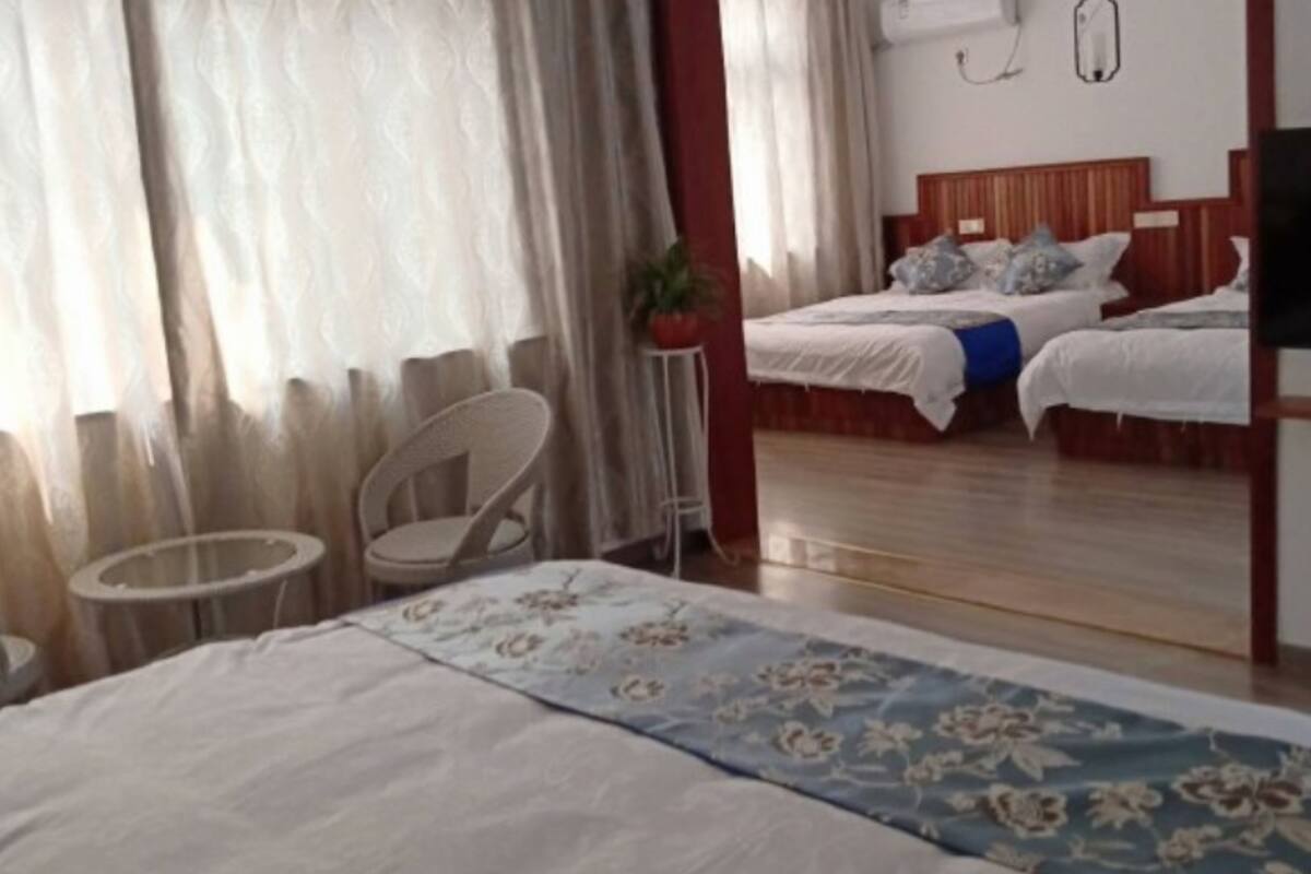 A hotel room with two beds, a small round table, a chair, and a large mirror.