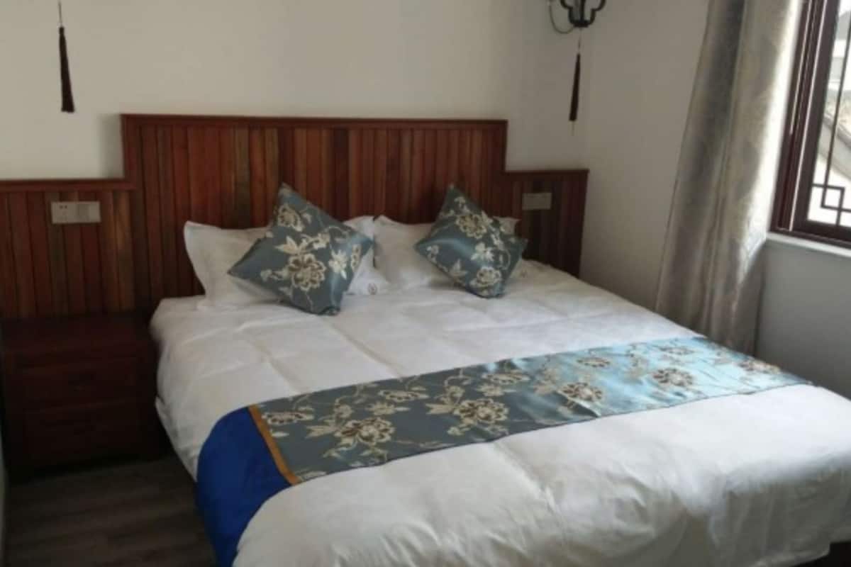 A bed with a wooden headboard, two pillows, and a floral bedspread.