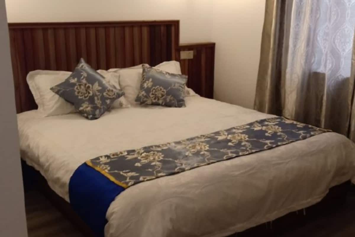 A neatly made bed with a floral bedspread and two decorative pillows.