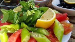 A table with a plate of fresh vegetables and a glass of red drink. - Alacati Sardunya Hotel (Cesme)