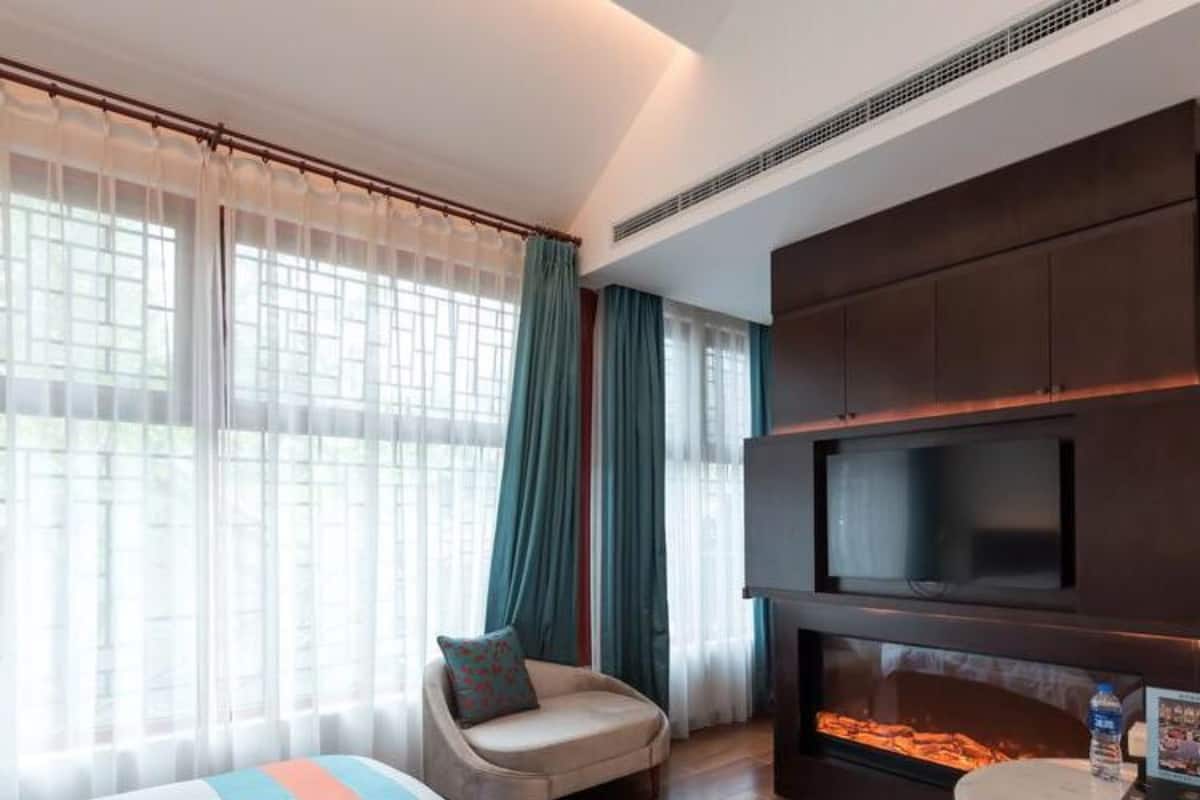A hotel room with two beds, a TV, a fireplace, and a chair.