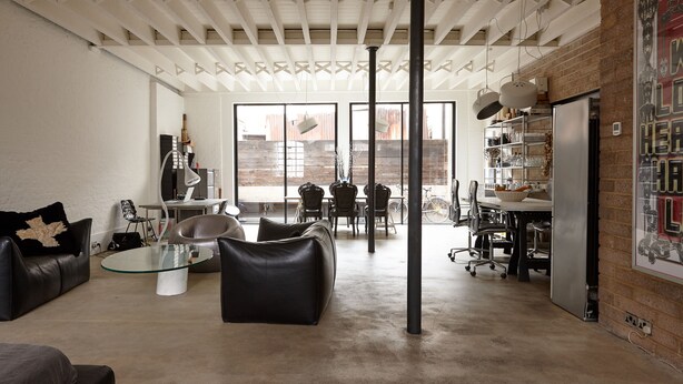 A spacious living area with a glass coffee table, leather sofas, and a dining area with chairs and a table.