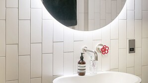 A bathroom with a white sink, a round mirror, and a towel hanging on the wall.