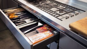 A kitchen with a built-in drawer containing kitchen utensils and a box of tissues.