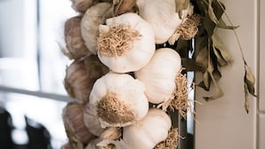 A wall adorned with a garland of onions and dried leaves.