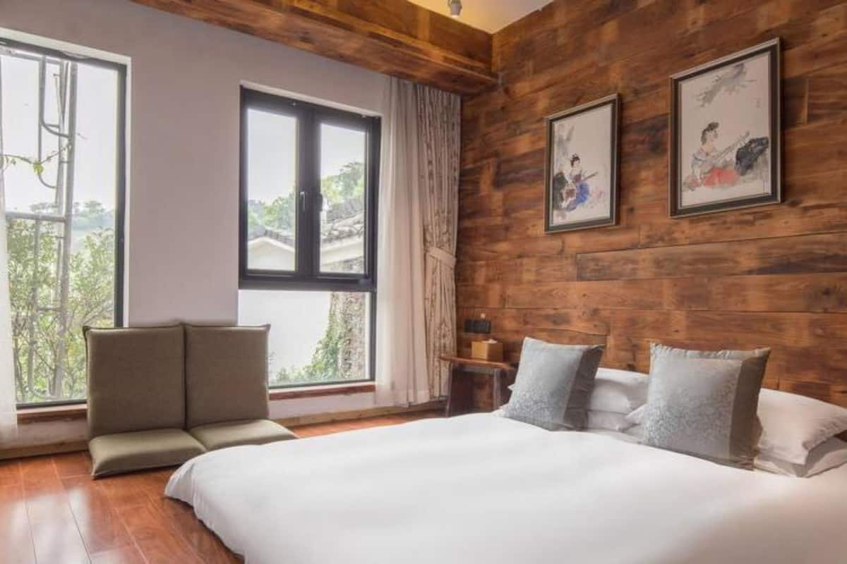 Un dormitorio con una cama grande, un sofá y dos ventanas.