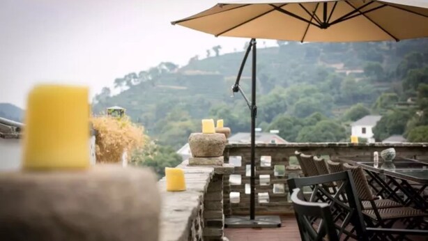 A terrace with stone railings, wicker furniture, and a view of a green landscape. - Floral Hotel Yuequ Yunshang (Hangzhou)