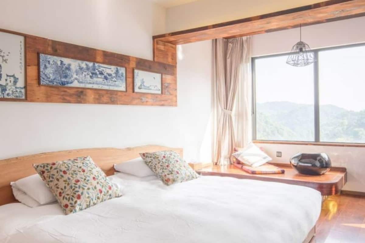 Un dormitorio con una cama grande, cabecera de madera y vistas a las montañas a través de una ventana.