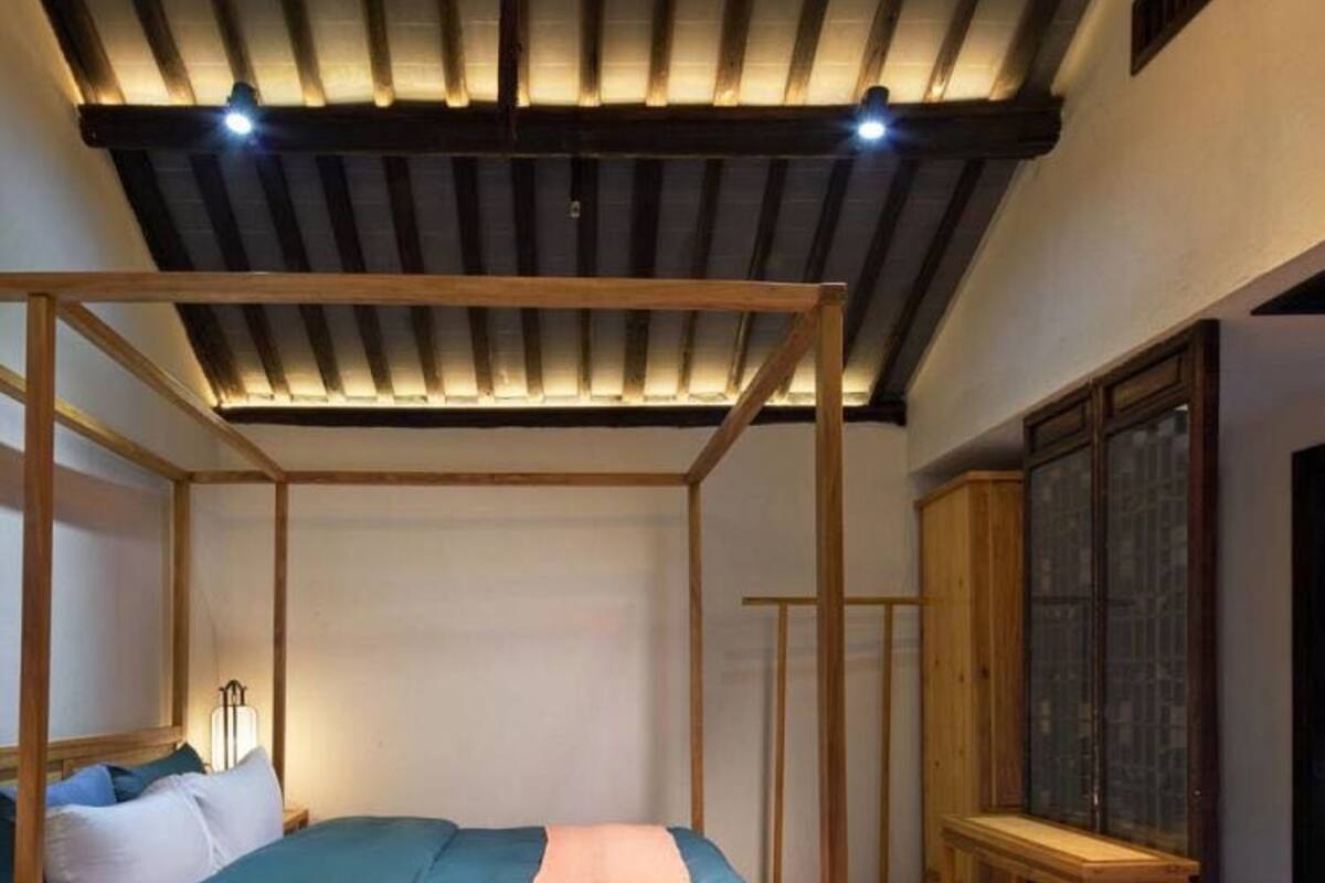 A four-poster bed with a wooden frame, a bedside table, and a wardrobe with glass doors.