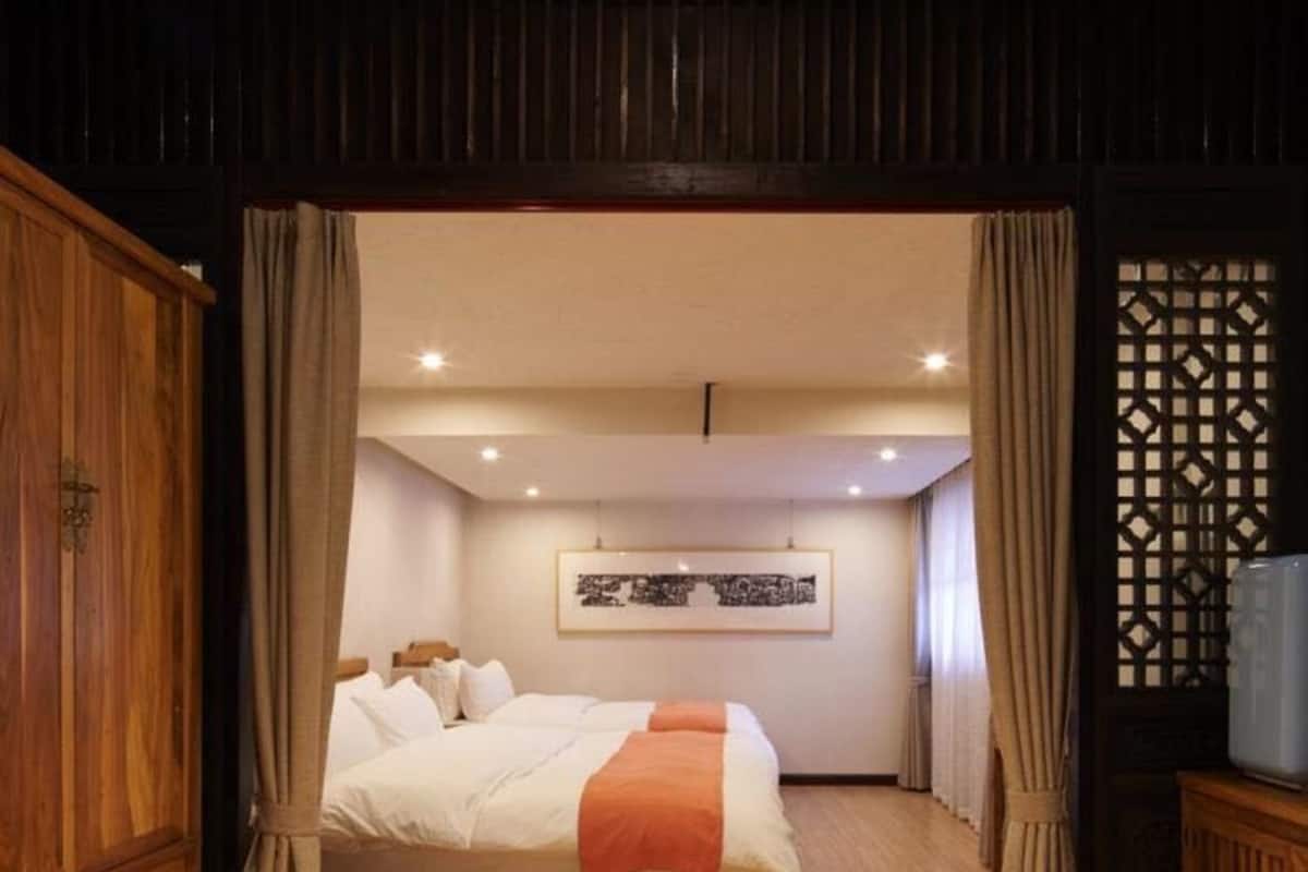 A bedroom with a wooden bed, a framed picture on the wall, and a traditional Japanese screen.