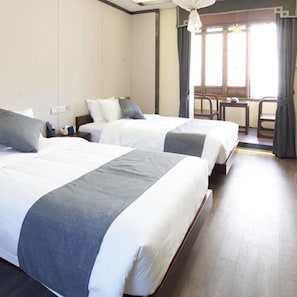 A hotel room with two beds, a small table, and a chair.