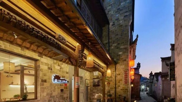 A narrow street with traditional stone buildings, wooden beams, and hanging lanterns. - Floral Hotel Xidi Muxishanfang (Huangshan)