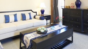 A living room with a sofa, a coffee table with a tray of items, a lamp, and a dresser. - Floral Hotel Xidi Muxishanfang (Huangshan)