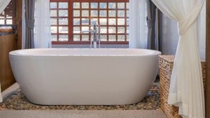 A modern bathroom with a freestanding bathtub, a wooden window with a grid pattern, and a stone-tiled floor. - Floral Hotel Xidi Muxishanfang (Huangshan)