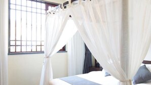 A bedroom with a bed, white curtains, and a window with bars. - Floral Hotel Xidi Muxishanfang (Huangshan)