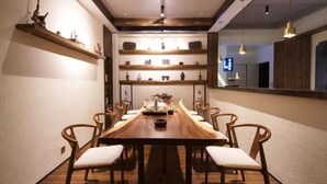 A dining area with a long wooden table, six chairs, and shelves with decorative items. - Floral Hotel Xidi Muxishanfang (Huangshan)