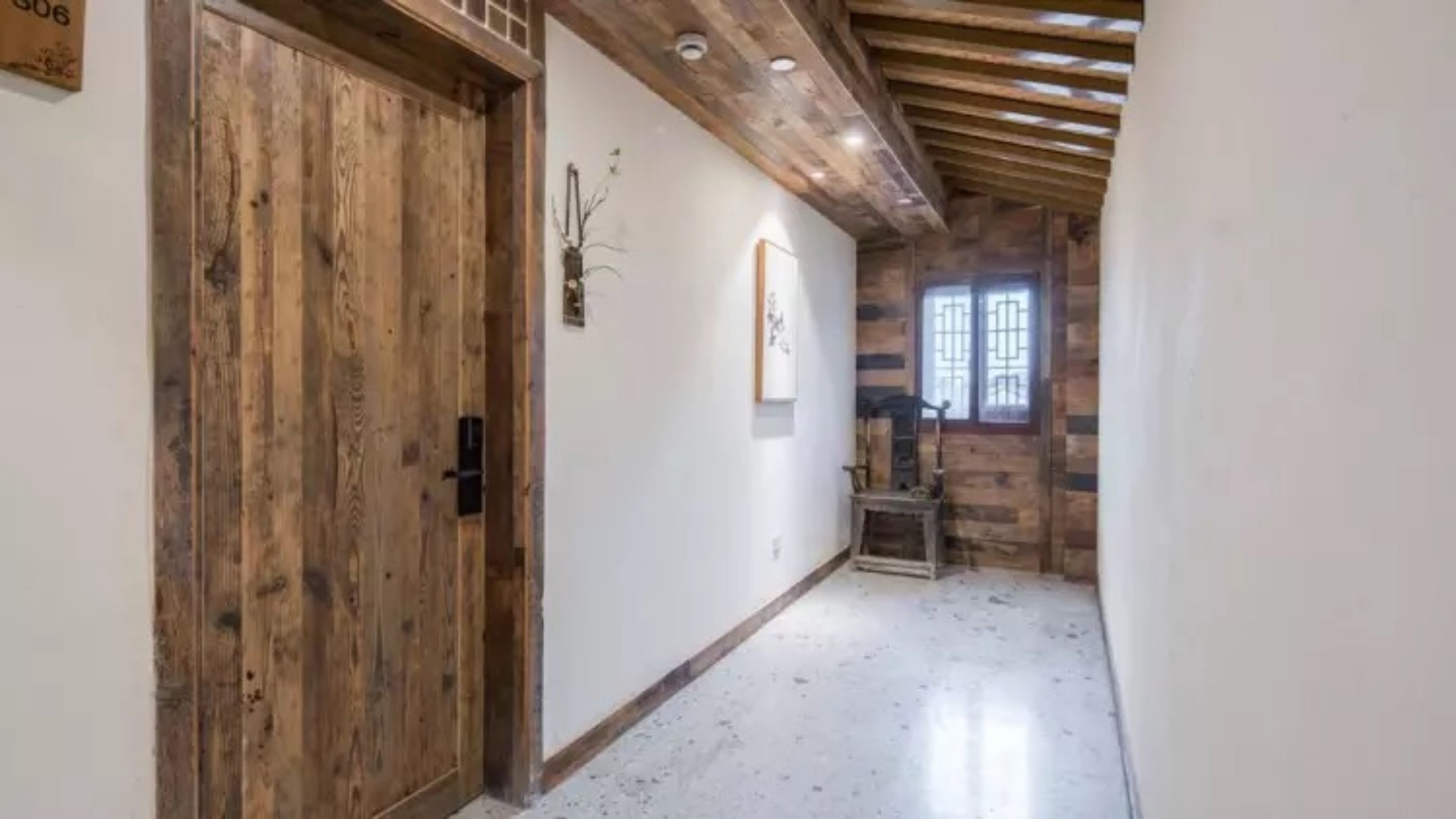 Ein Flur mit einer Holztür, einem kleinen Tisch und einem Fenster mit Gitterstäben.