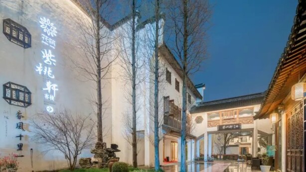 A traditional building with a sign in Chinese characters, a courtyard with trees, and a reflection on the ground. - Zitaoxuan Inn (Jiaxing)