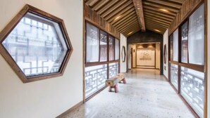 A corridor with wooden beams, hexagonal windows, and a bench. - Zitaoxuan Inn (Jiaxing)