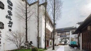 A traditional courtyard with stone lanterns, a wooden gate, and a building with a tiled roof. - Zitaoxuan Inn (Jiaxing)