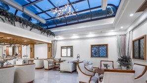 A spacious living area with a high ceiling, large windows, and a modern chandelier. - Zitaoxuan Inn (Jiaxing)