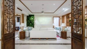 A spacious living room with a white sofa set, two side tables with lamps, a green vertical garden, and a ceiling fan. - Zitaoxuan Inn (Jiaxing)