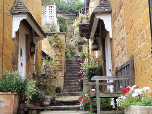 A narrow stone staircase with steps leading up to a wooden door, flanked by potted plants and flowers. - Bridge Farm Holiday Cottages (Evesham)