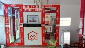 A reception area with a red and white color scheme, a chandelier, a reception desk, a bench, and a patterned floor. - Surigao Tourist Inn Main (Surigao)