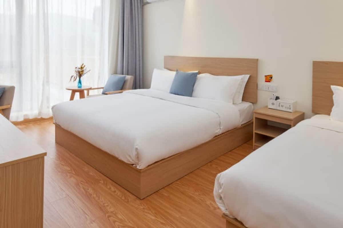Quarto de hotel com uma cama grande, mesas de cabeceira e uma janela com cortinas.