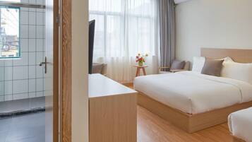 Quarto de hotel moderno com uma cama grande, uma escrivaninha, uma cadeira e uma televisão.
