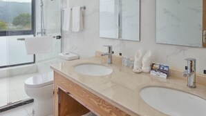 Une salle de bain moderne avec deux lavabos, des toilettes et une douche à parois de verre.