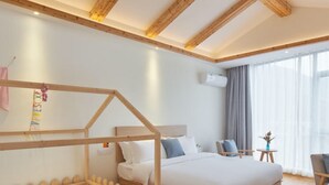 Une chambre d’hôtel avec deux lits, des poutres en bois au plafond, une petite table avec un vase et une fenêtre avec des rideaux.